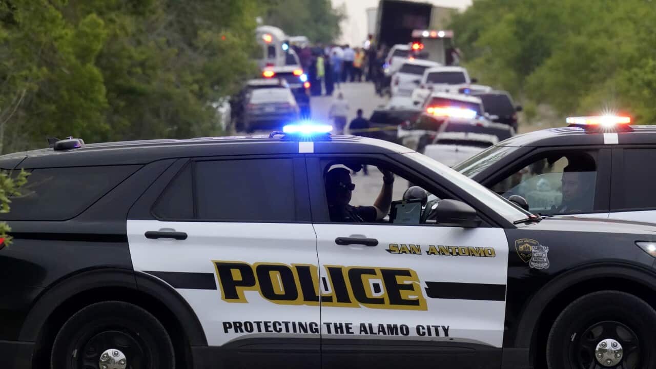 Police cars blocking a road where there is a semitrailer parked on the side.