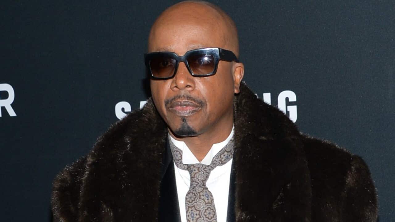 MC Hammer poses for a photo wearing a suit, fur coat and sunglasses