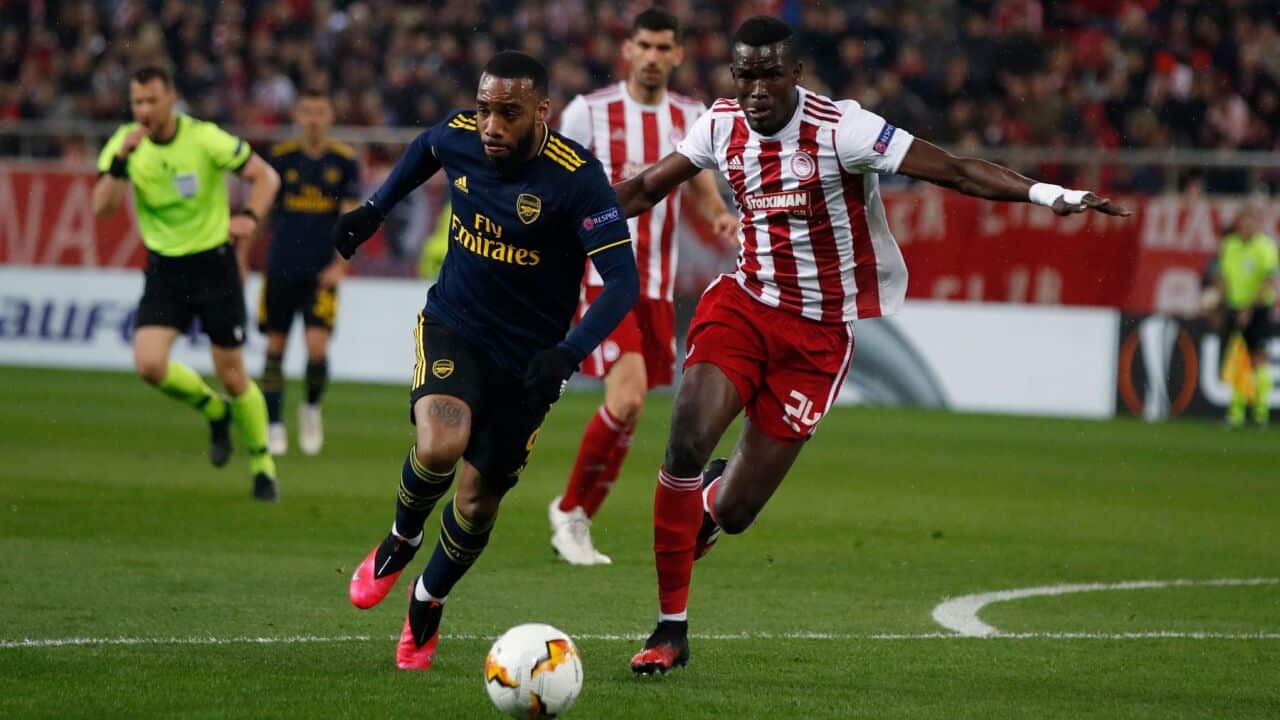 Arsenal's Alexandre Lacazette, left, runs for the ball next to Olympiakos' Ousseynou Ba during the Europa League round of 32, first leg, soccer match.