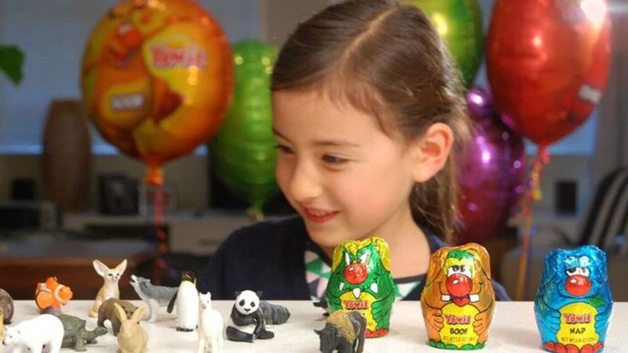 child playing with toys from inside chocolate Yowies.