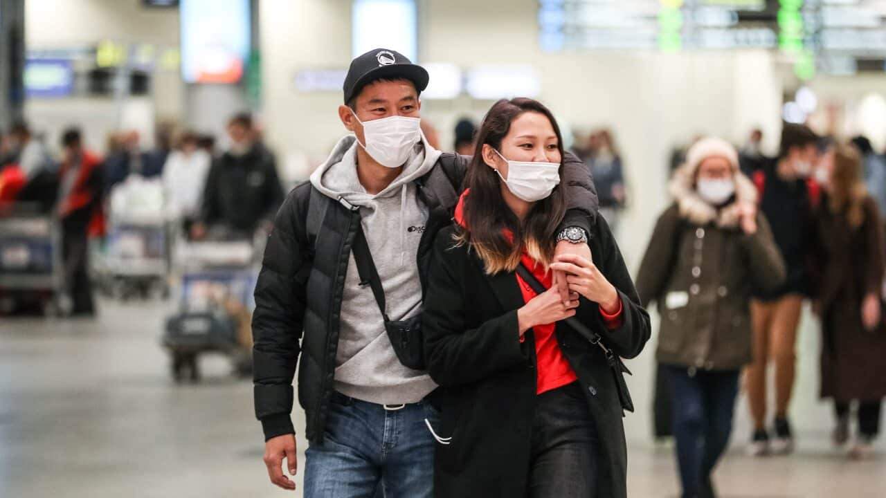 Two travellers wearing face masks at an airport.