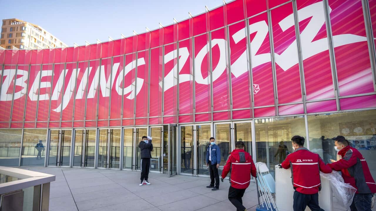 Workers deliver a cart loaded with equipment to a commercial plaza at the Winter Olympic Village in Beijing,