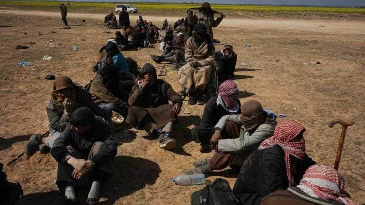 Men wait to be screened after being evacuated out of the last territory held by Islamic State militants.