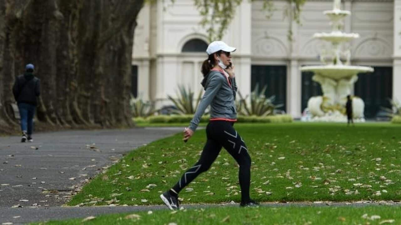 A person wearing a face mask is seen walking through Carlton Gardens