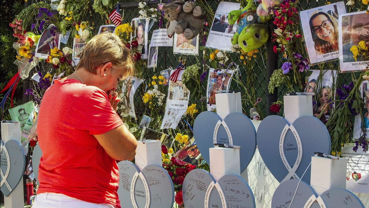 A woman mourns at the memorial wall for the victims of the Champlain Towers South collapse