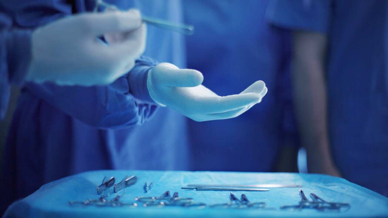Handing doctor surgical tool in operating room. (Stock)