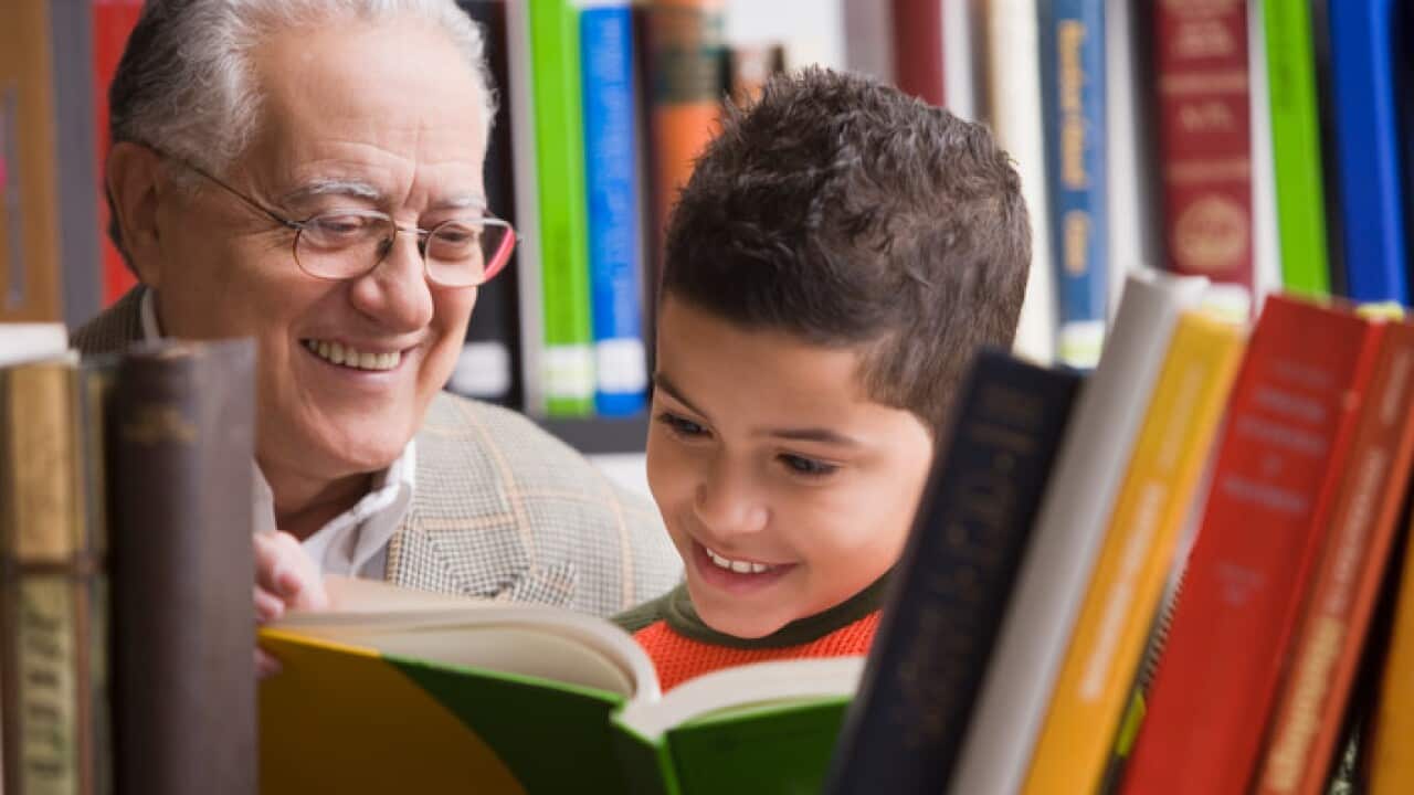 Young boy and grandfather reading in library