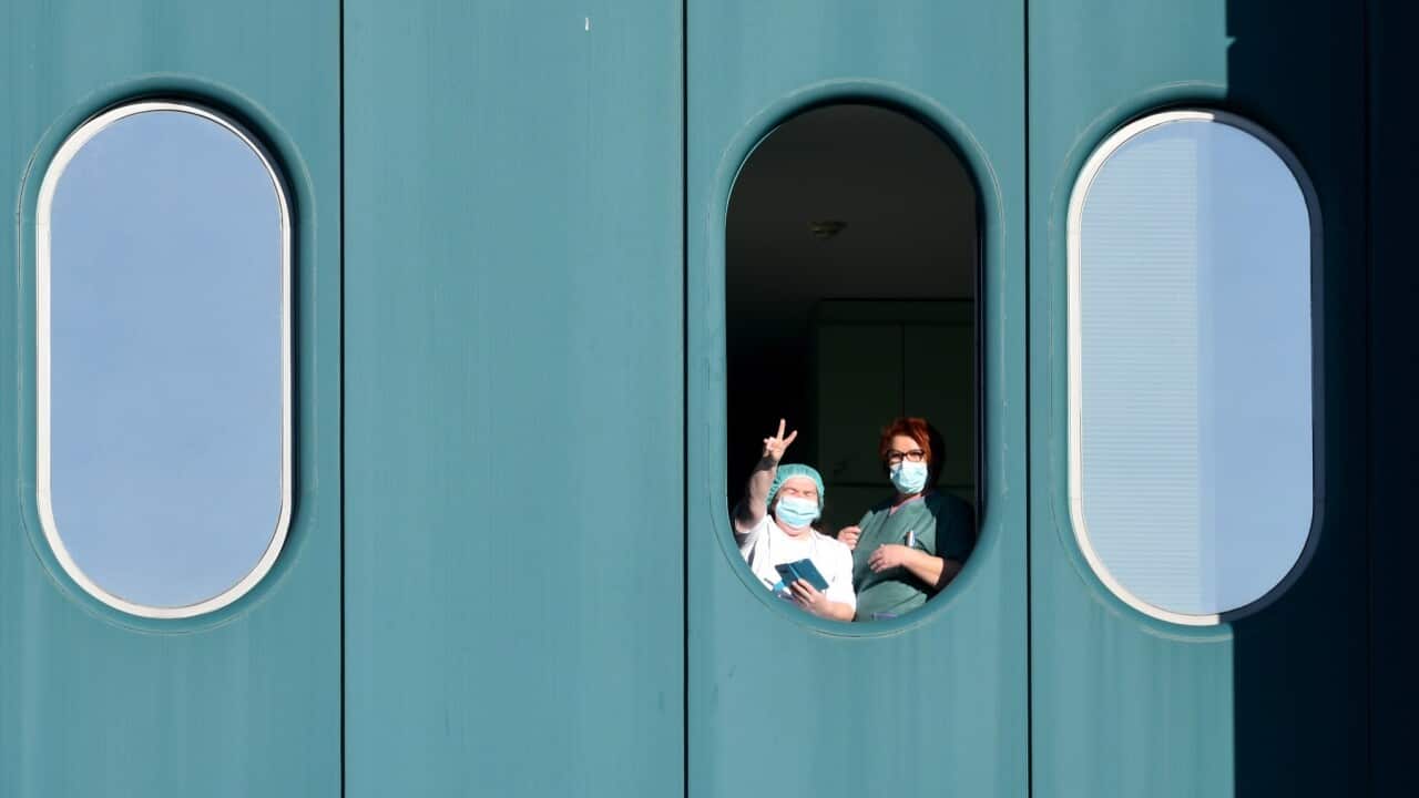 Medical staff show victory sign to the media at the window of the Dubrava hospital on March 15, 2020. - Patients from Zagreb clinical hospital KB Dubrava are evacuated since two of its doctors were tested positive to the coronavirus. The hospital will bec