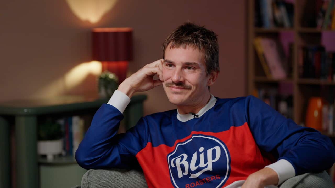 A man sitting in a chair in a blue and red shirt