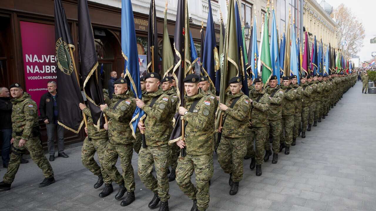Military personnel holding flags march in Vukovar, Croatia, Thursday, Nov. 18, 2021.
