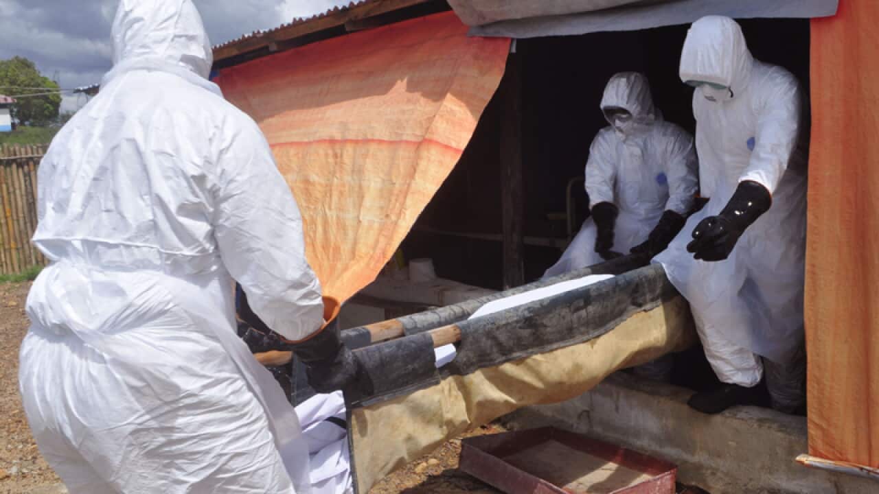 Ebola health care workers carry the body of a woman , Liberia,