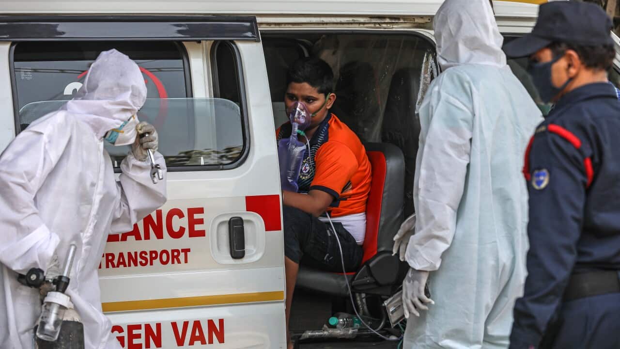 Health workers attend to a suspected COVID-19 patient waiting outsidee a health centre in Mumbai, India, 19 April 2021.