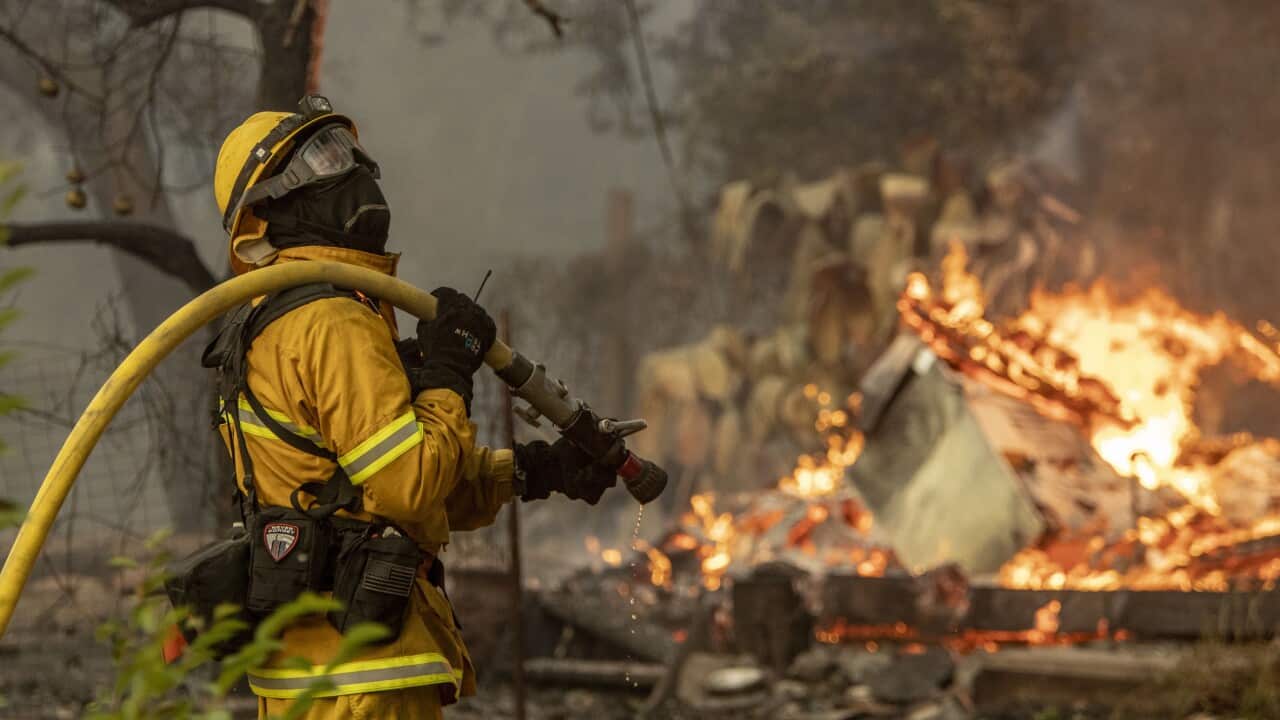 A firefighter keeps an eye on the exposure of a house.
