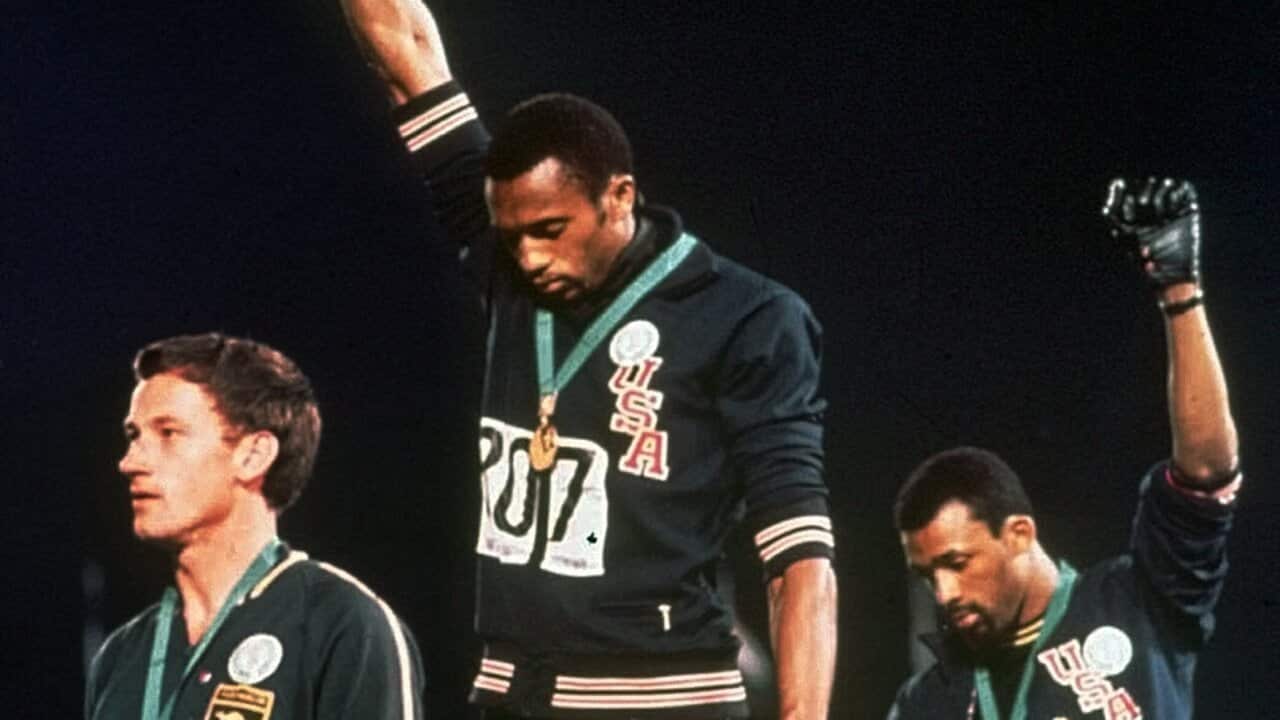 At the 1968 games, Australian silver medalist Peter Norman stands beside US Athletes Tommie Smith and John Carlos as they raise their gloved hands in protest.