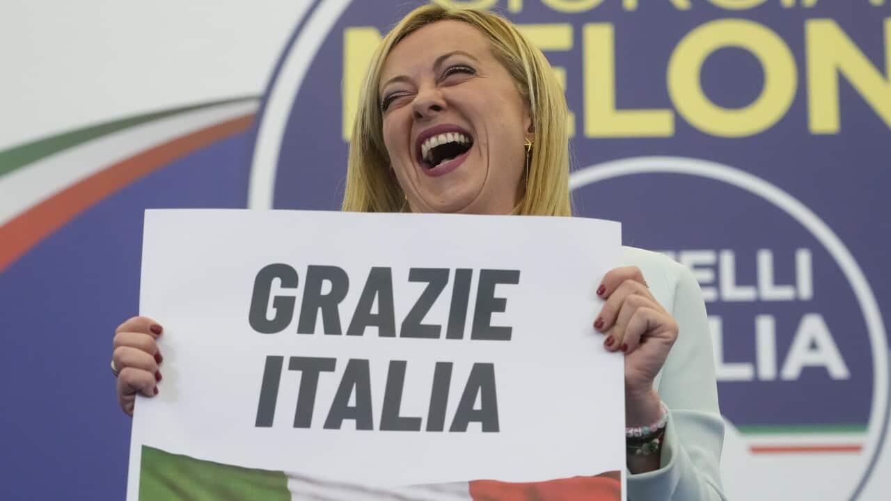A blonde woman holds a sign reading: "grazie Italia"