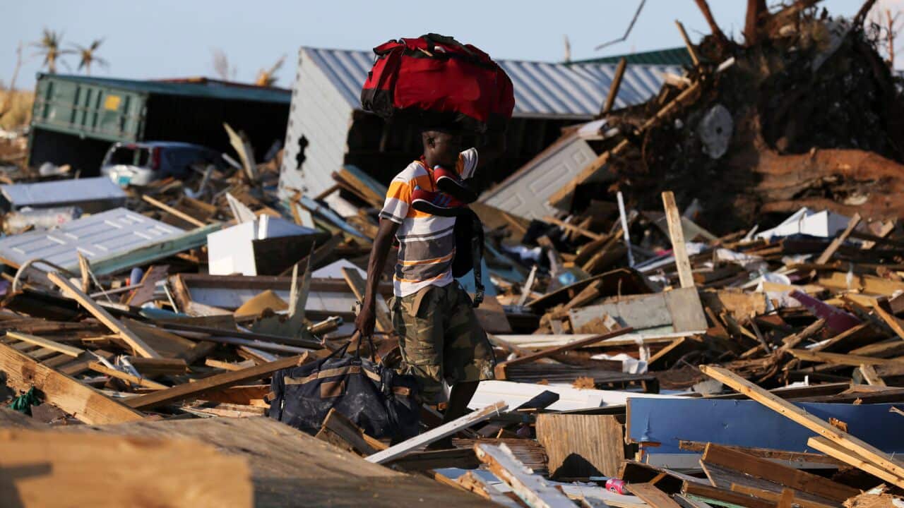 A man carries his belongings in an area called The Mudd after it was devastated by Hurricane Dorian