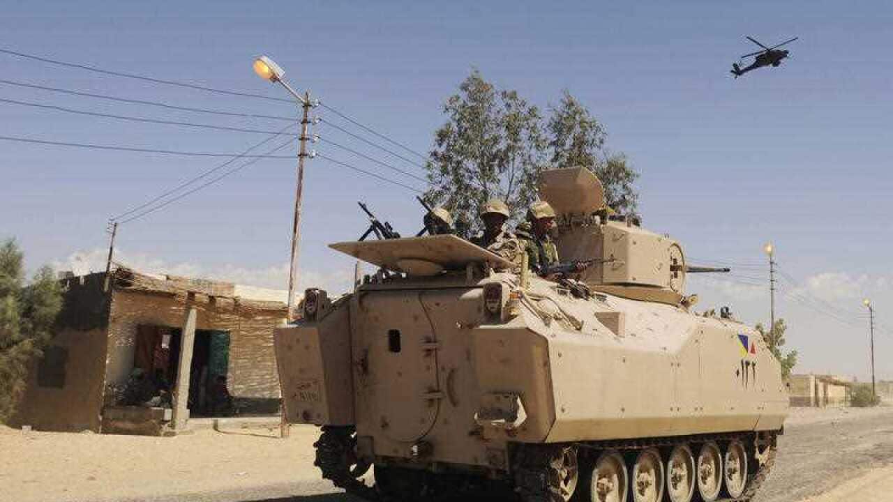 Egyptian Army soldiers patrol in an armored vehicle backed by a helicopter gunship
