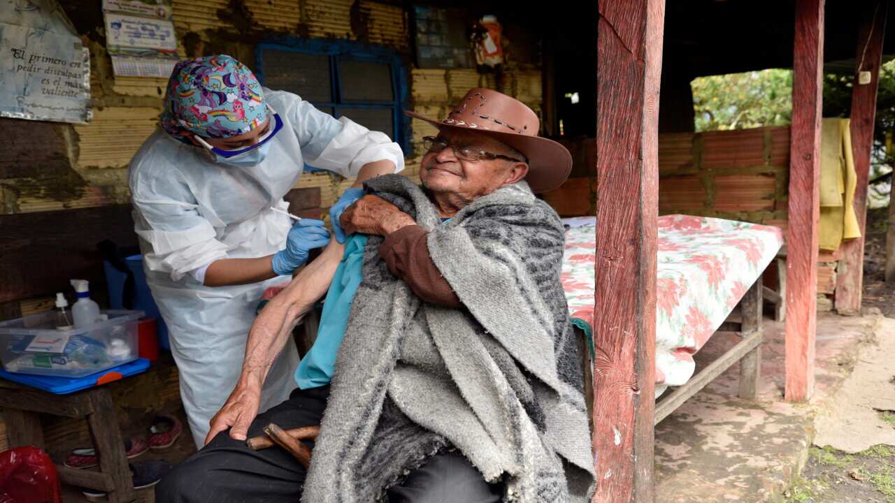 A nursing assistant gives a shot to an elderly man during a door-to-door vaccination campaign in rural areas of Bogota.