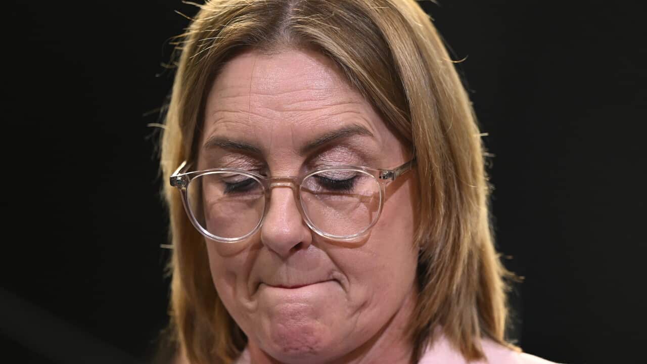 A middle-aged white woman, looking down with a grimace.