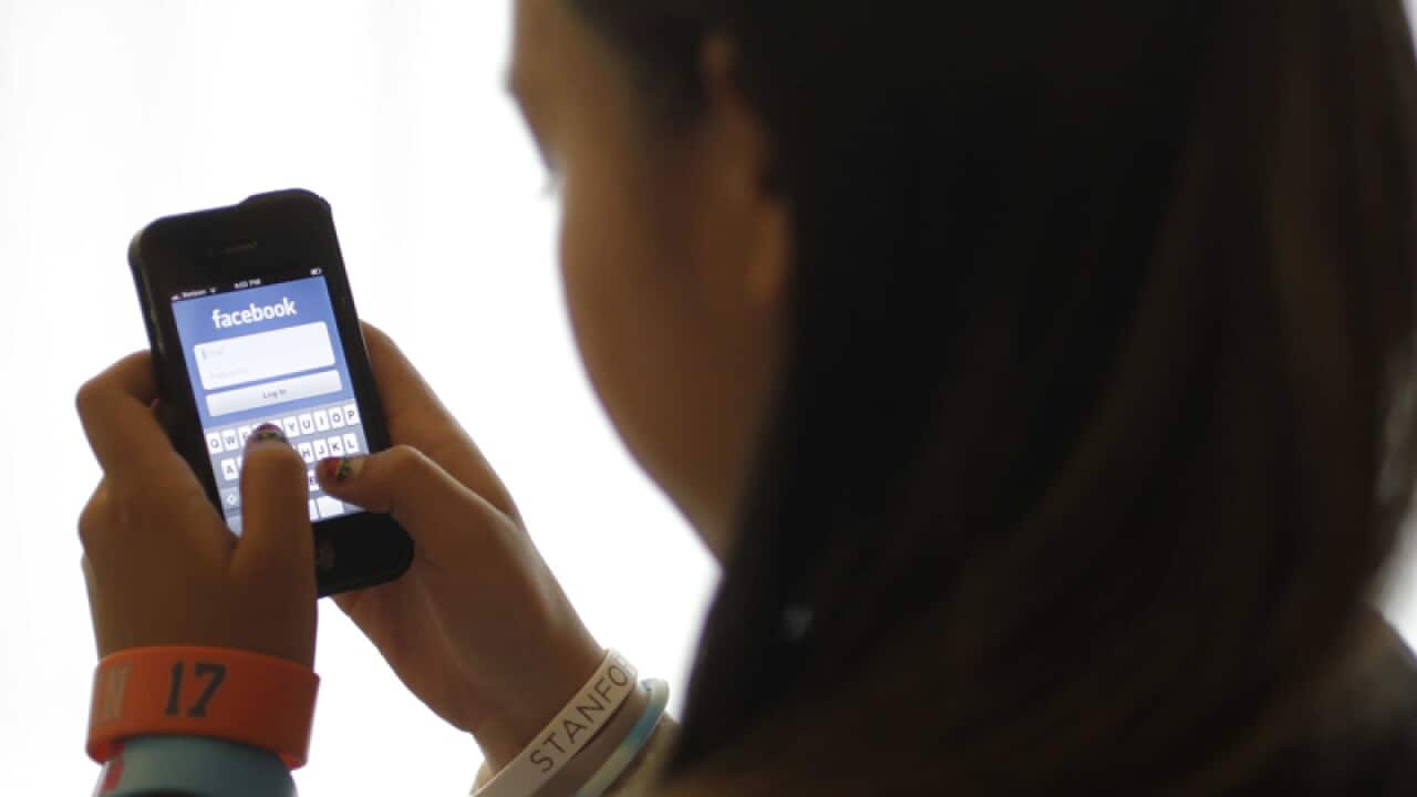 A girl logs into Facebook on her phone