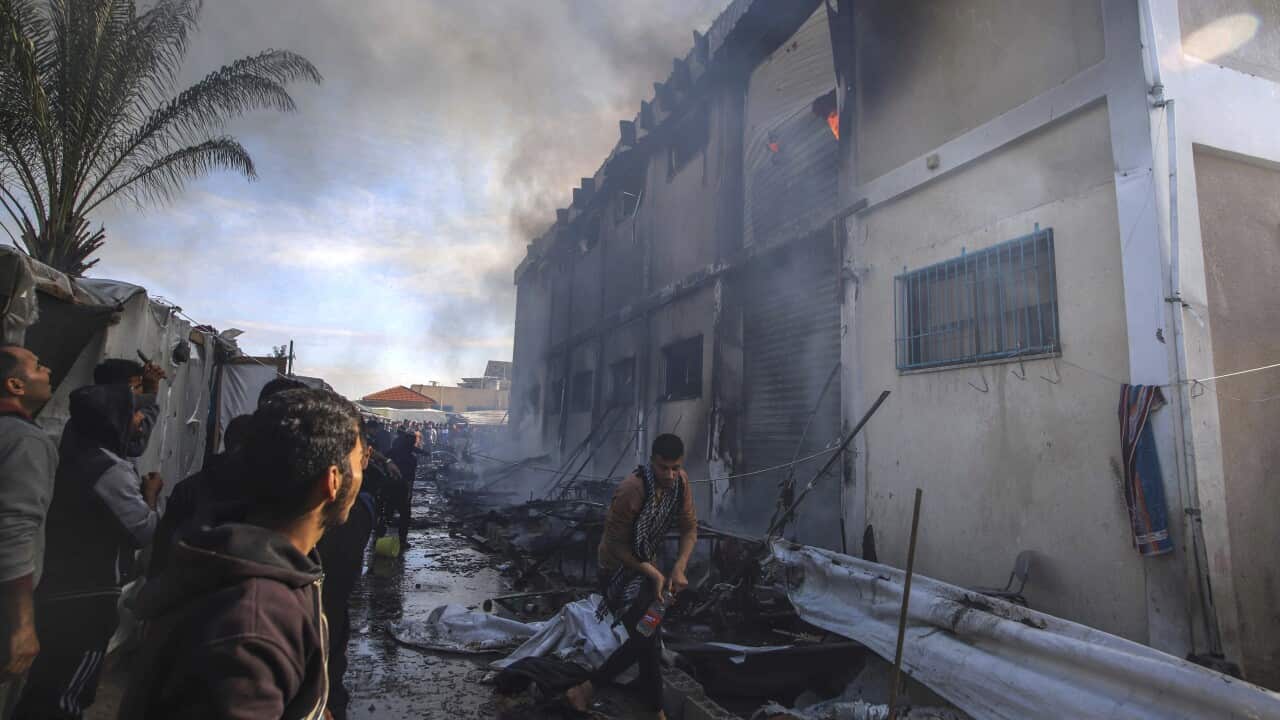 A small group of people outside a burning two-storey building