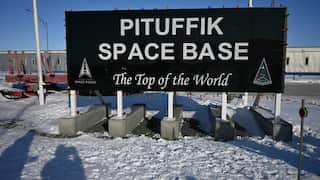 Sign reading “PITUFFIK SPACE BASE” and “The Top of the World” stands on a snow-covered site, with US Space Force logos and low buildings visible in the background.