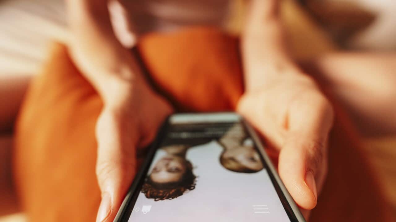 Hand holding smartphone shopping online at home in casual setting