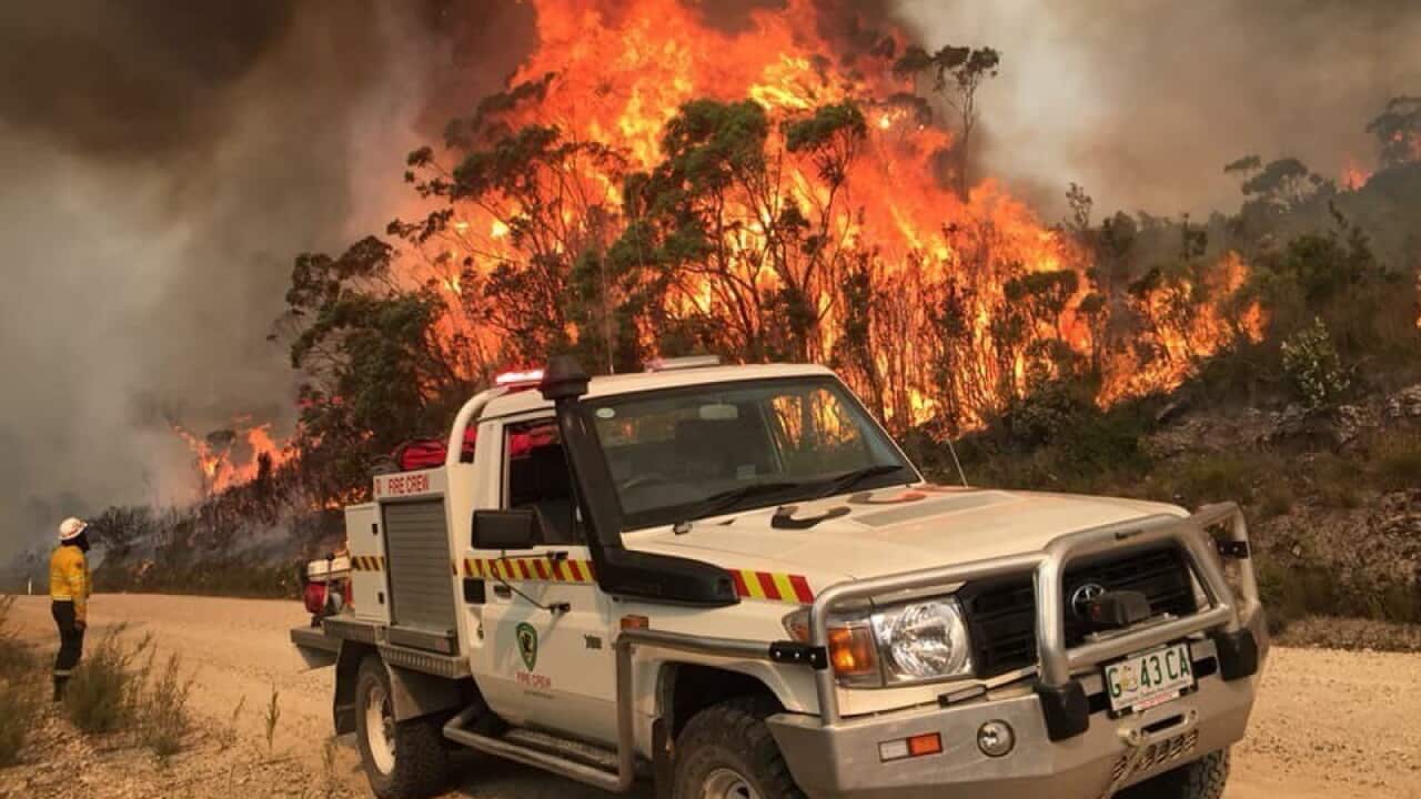 A file image of a Tasmania Parks and Wildlife Service firetruck parked on the roadside as a bushfire burns in Miena.