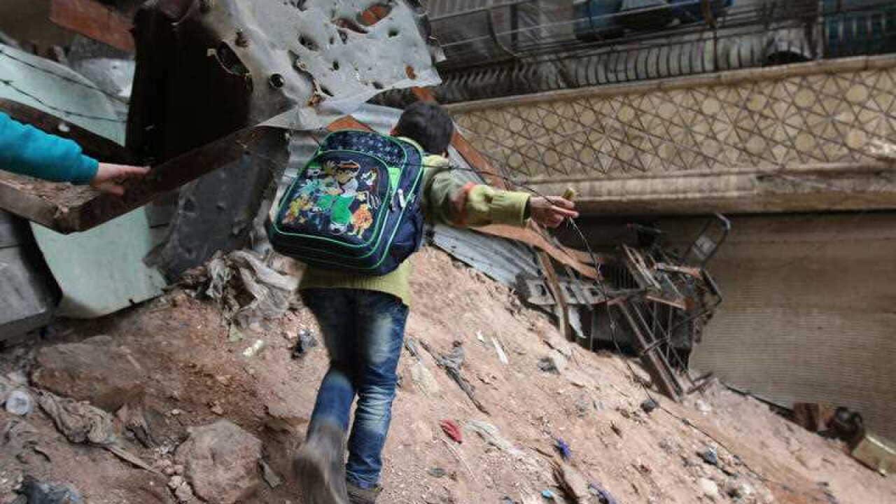 A child navigates through rubble and barbed wire in Aleppo. (AAP)