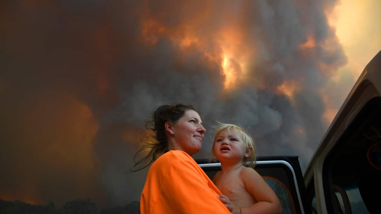 Sharnie Moran and her 18 months old daughter Charlotte look on as thick smoke rises from bushfires near Nana Glen, near Coffs Harbour,