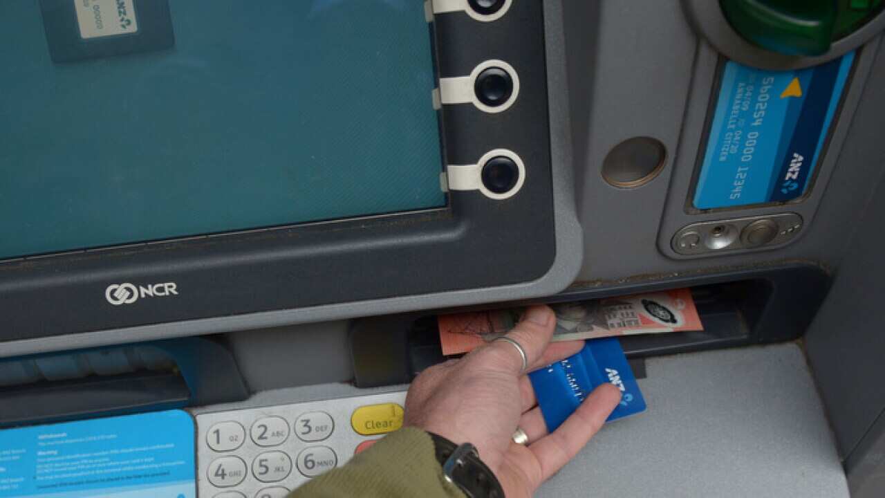A customer uses an ANZ automatic teller machine to withdraw cash.