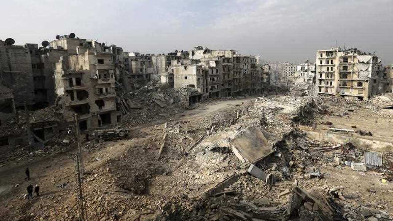 People walk through mounds of rubble which used to be high-rise apartment buildings in the once rebel-held Ansari neighborhood in eastern Aleppo, Syria.