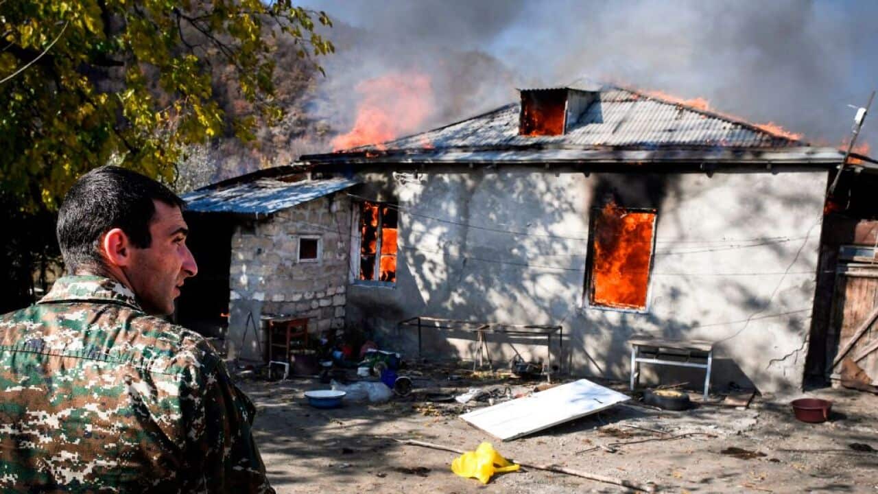A man looks on as a house burns in the village of Charektar outside the town of Kalbajar on November 14, 2020