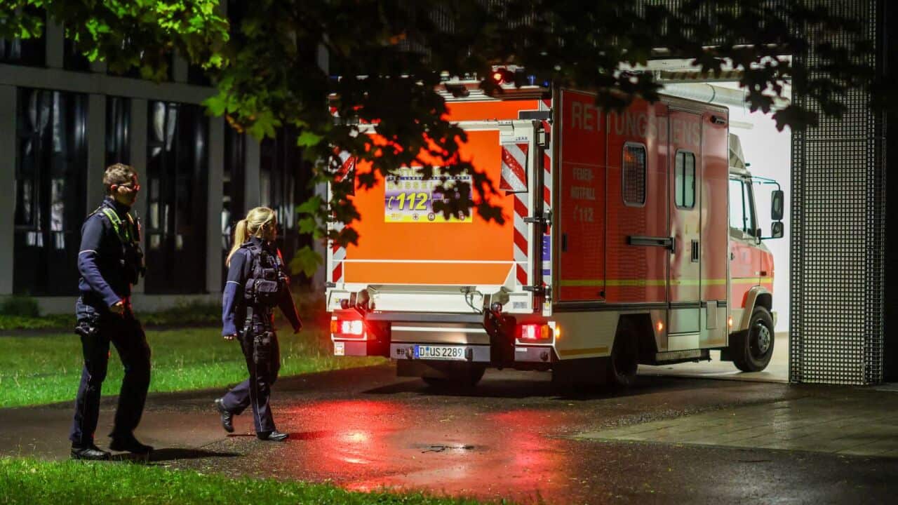 Police officers walk past an arriving ambulance taking a German patient to the infection center at Düsseldorf University Hospital, Wednesday, May 6, 2026, in Düsseldorf, Germany. (Christoph Reichwein-dpa via AP).jpg