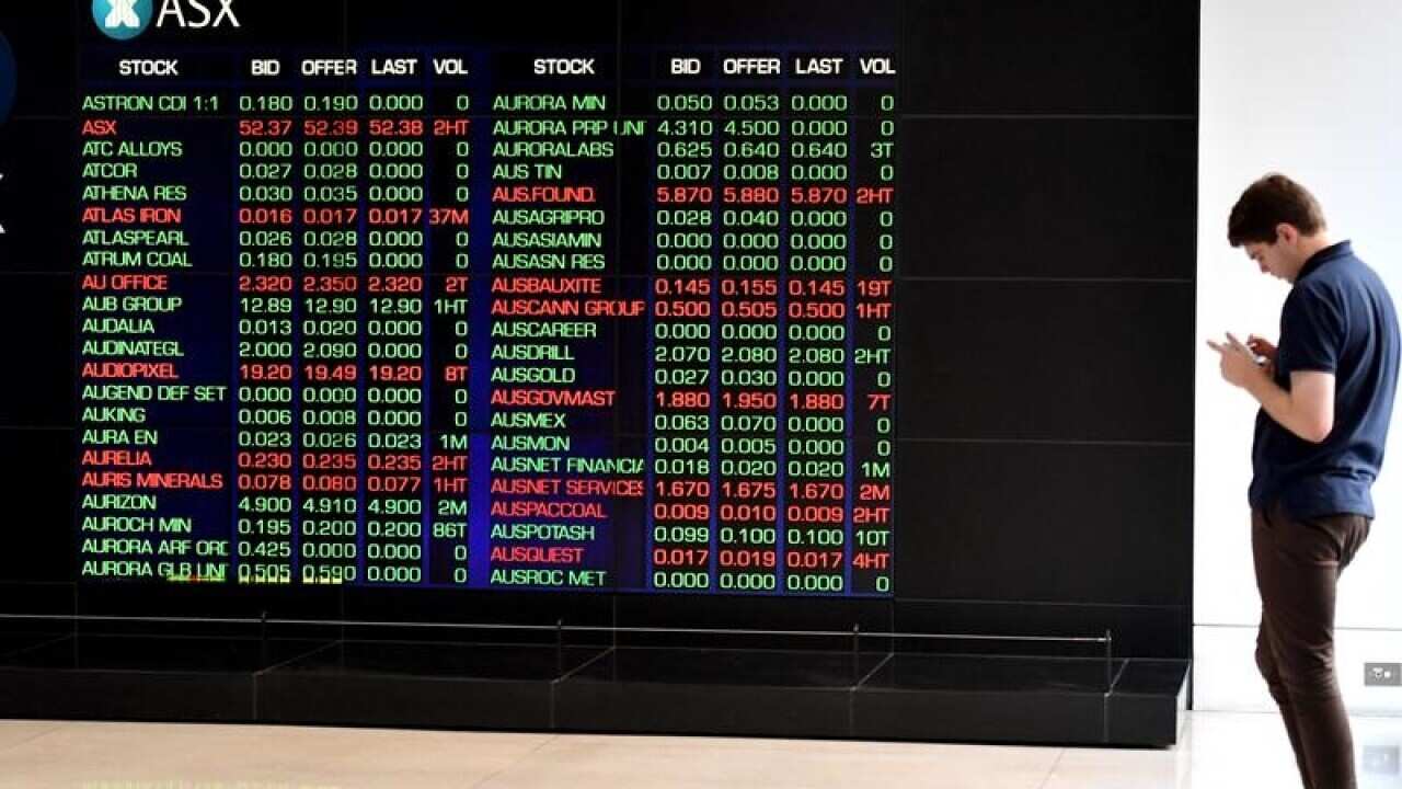 Man looking at mobile phone near ASX Board