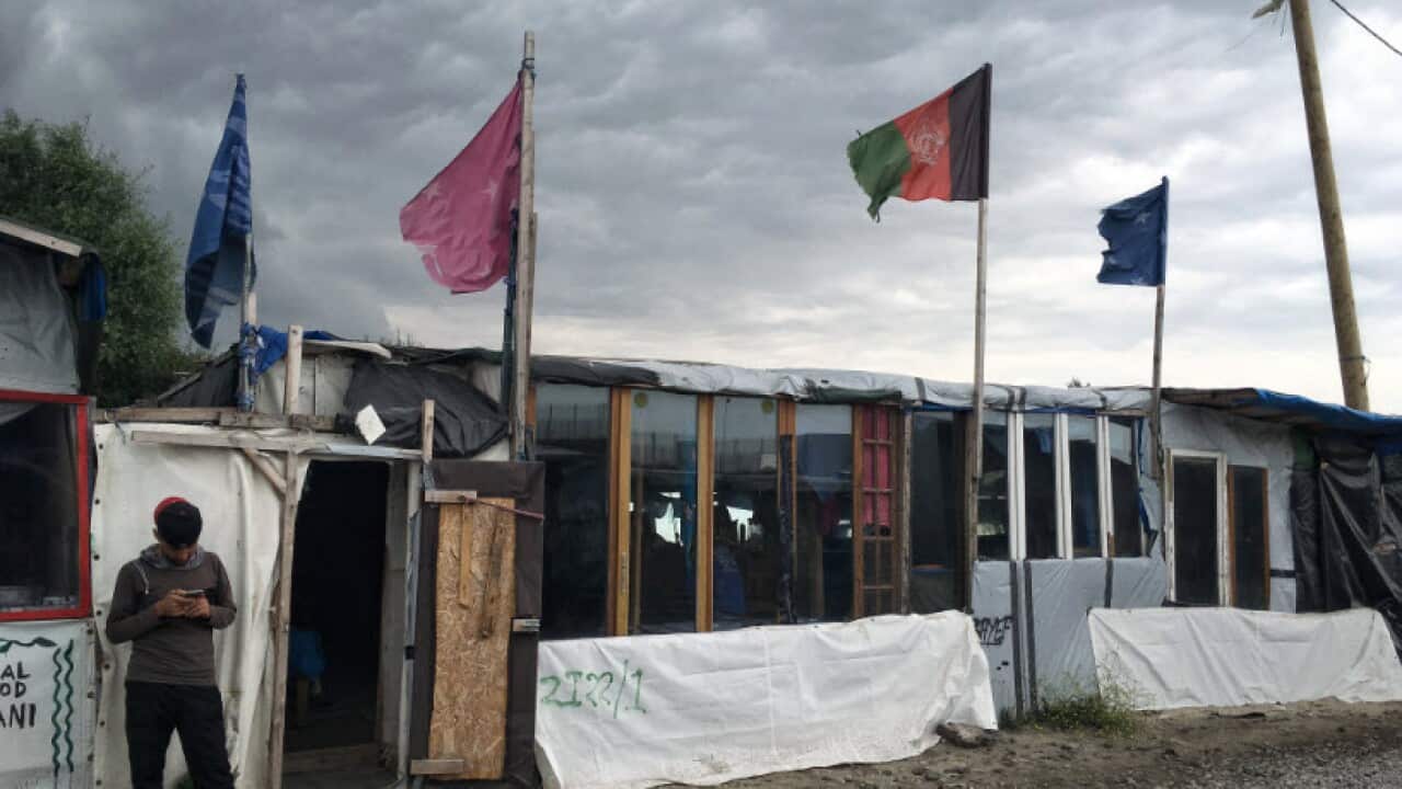 A boy waits outside shelters at the Calais Jungle in France.