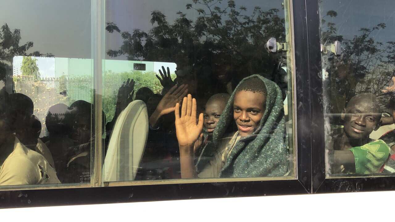 A child waves his hand from a bus as children kidnapped by Boko Haram in Nigeria return to their parents after having been freed on 18 December, 2020.