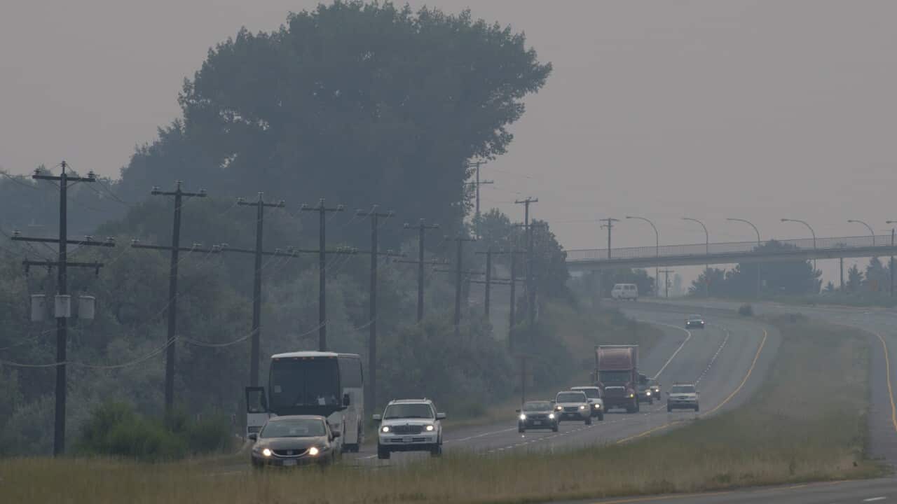 Cars and trucks drive though the thick smoke caused by wildfires just outside of Kamloops, B.C., on Sunday, July 16, 2017.