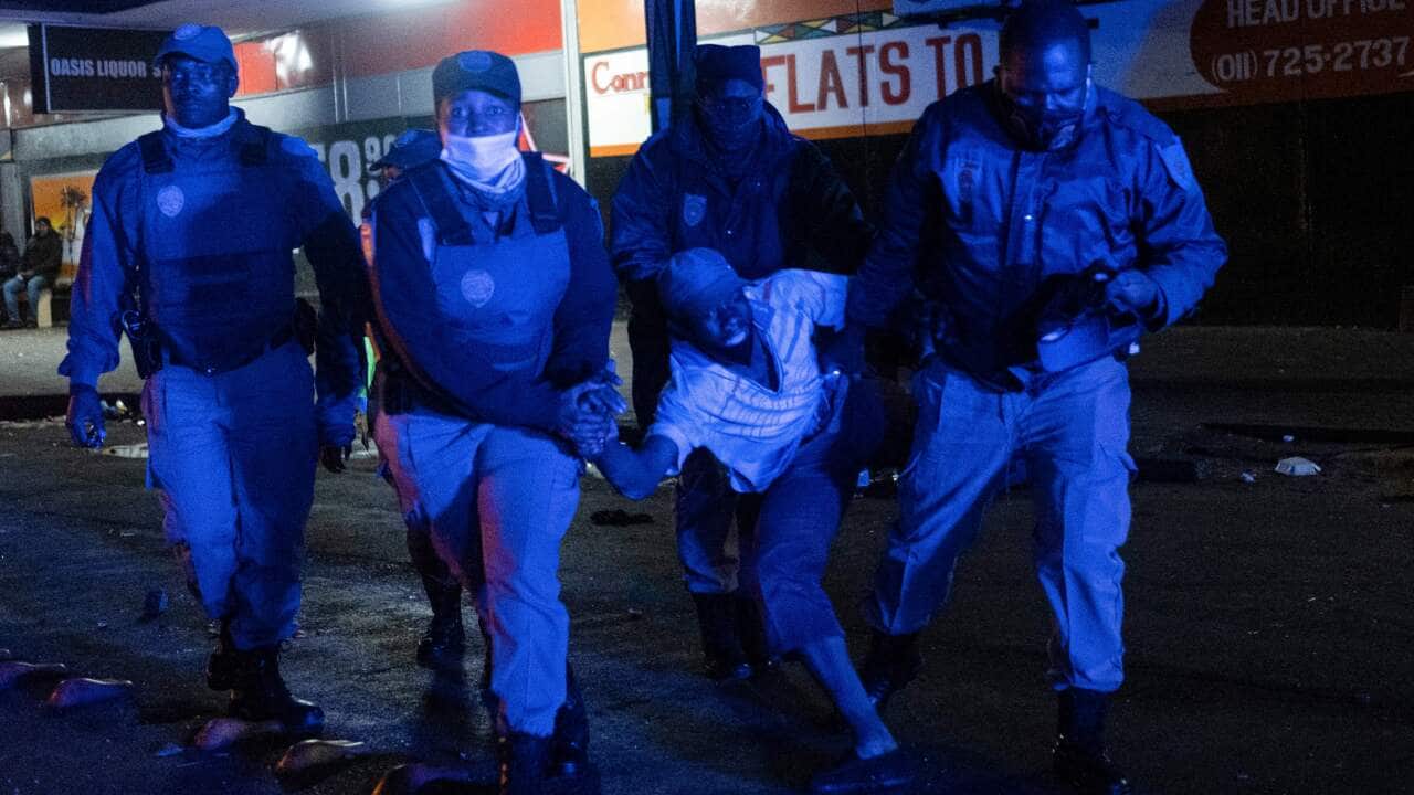 Johannesburg Metro Police Department (JMPD) officers detain a suspected looter in the central business district in Johannesburg