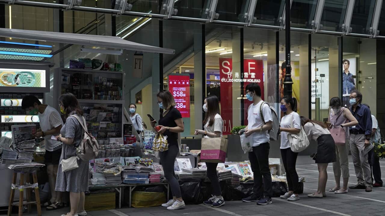 People queue up at a news stand to buy copies of Apple Daily at a down town street in Hong Kong Tuesday, Aug. 11, 2020