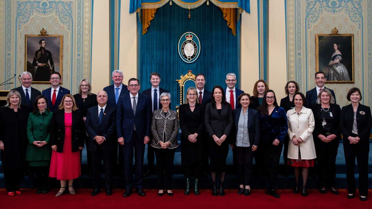 Men and women wearing formal attire standing and posing for a photo.