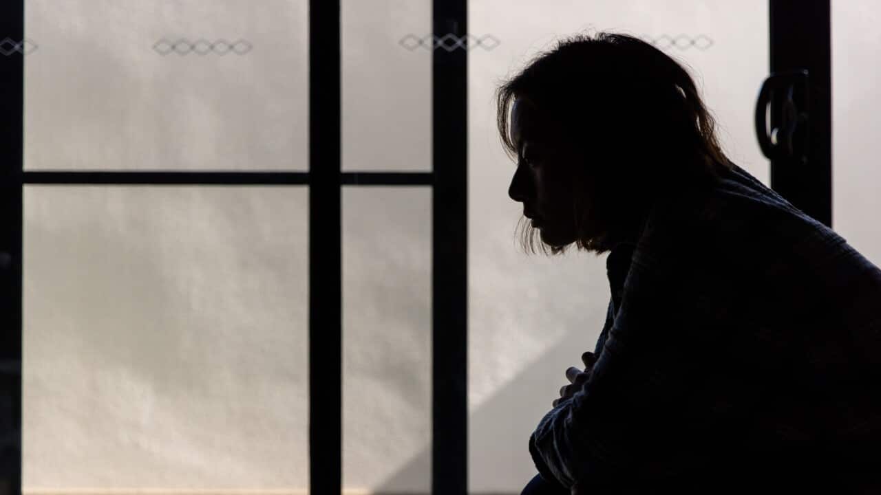 A silhouette of a woman sitting on a bed