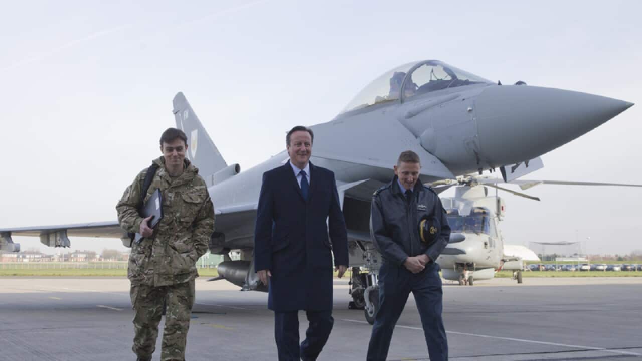 British PM David Cameron (centre) walks past an RAF fighter jet