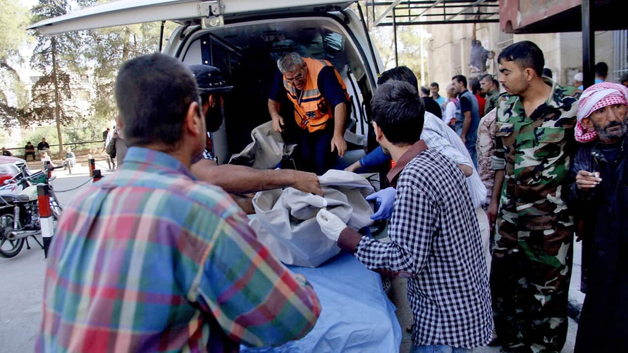 A file photo of men standing next to an ambulance with a body of a dead child from the national school in Aleppo, Syria.