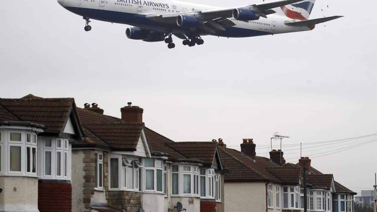 A plane nearby houses at Heathrow Airport.