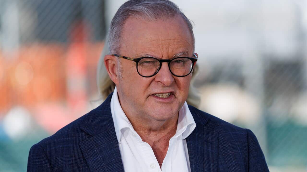 A middle-aged white man wearing glasses, a navy blazer and white shirt