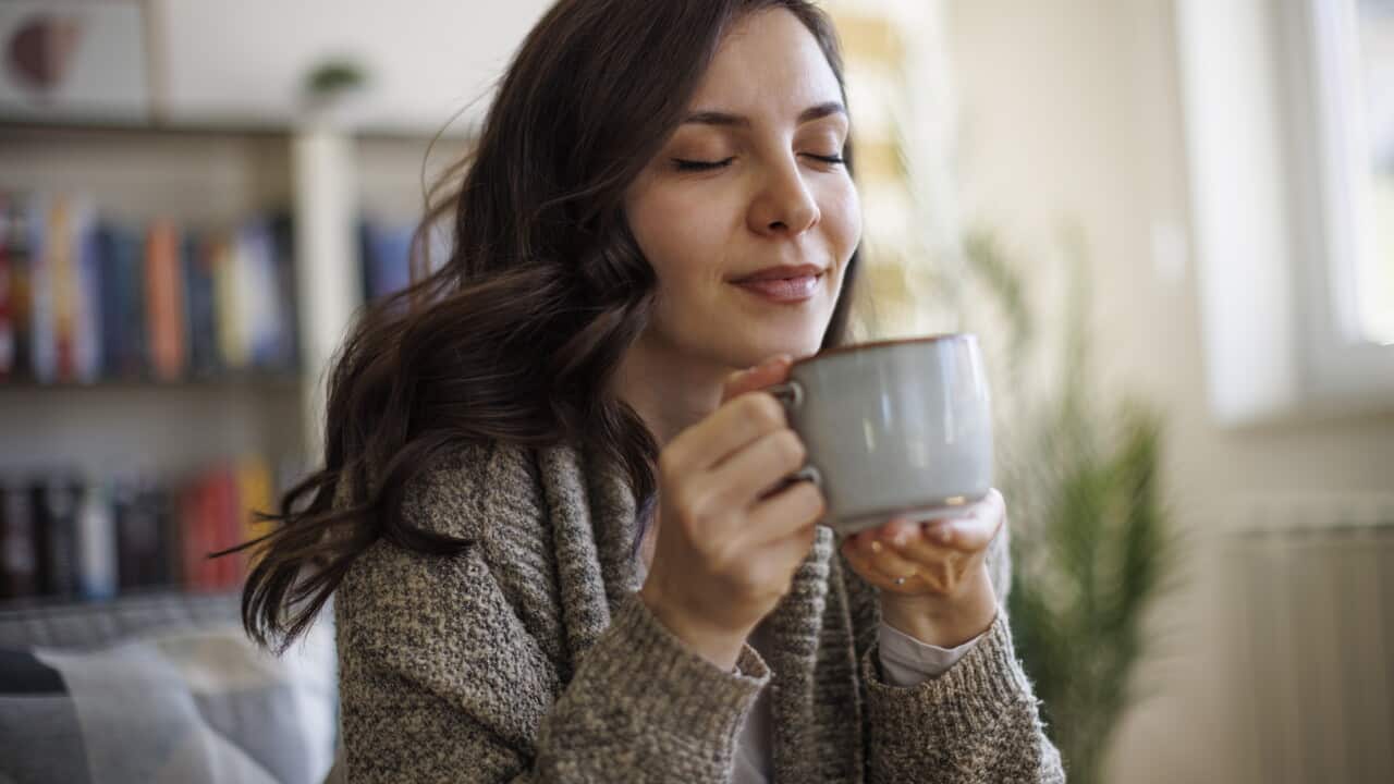 Young smiling woman enjoying in smell of fresh coffee at home