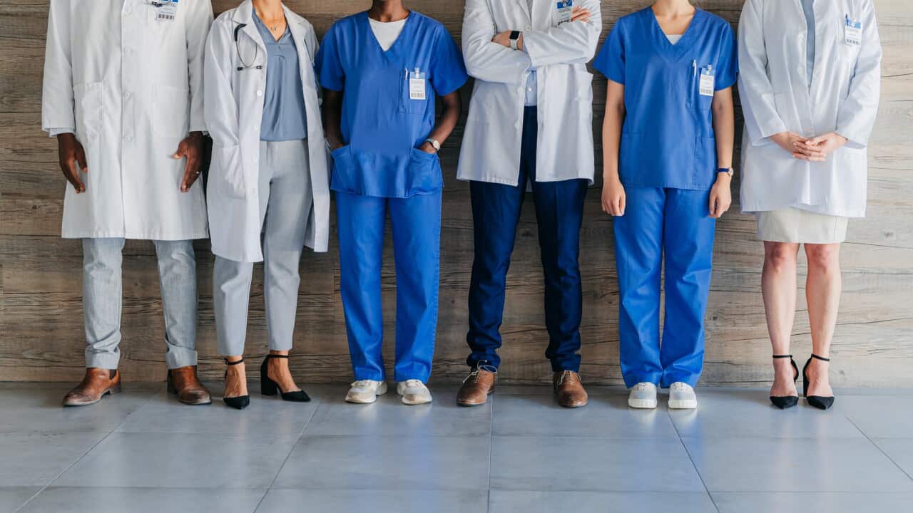 Team of professional, medical coworkers, against wood background, together show diversity, in hospital corridor. Group of doctors and nurses, against brown backdrop, in clinic or healthcare facility.