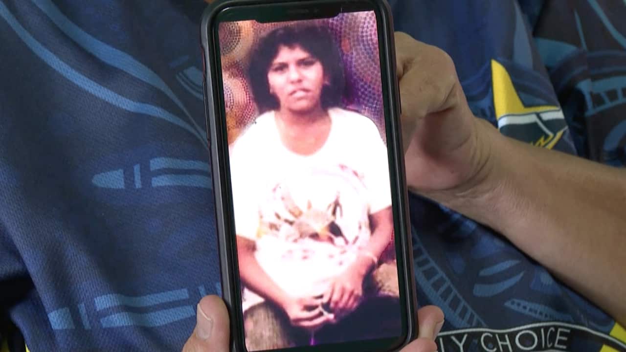One of Ms Fisher-Tilberoo's sisters holds a photo of her on a mobile phone.