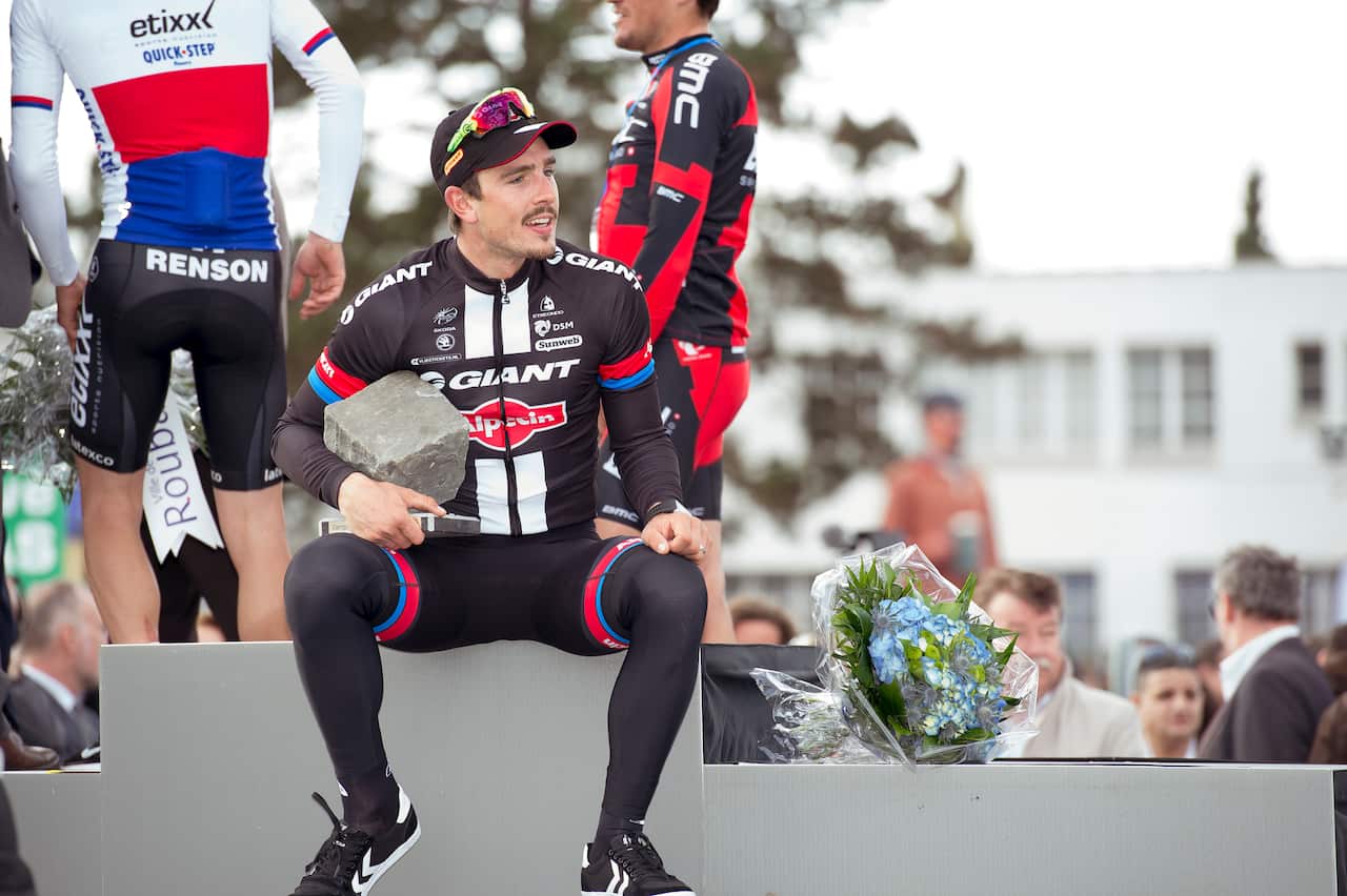John Degenkolb sits on the podium with the cobbled trophy from Paris-Roubaix.